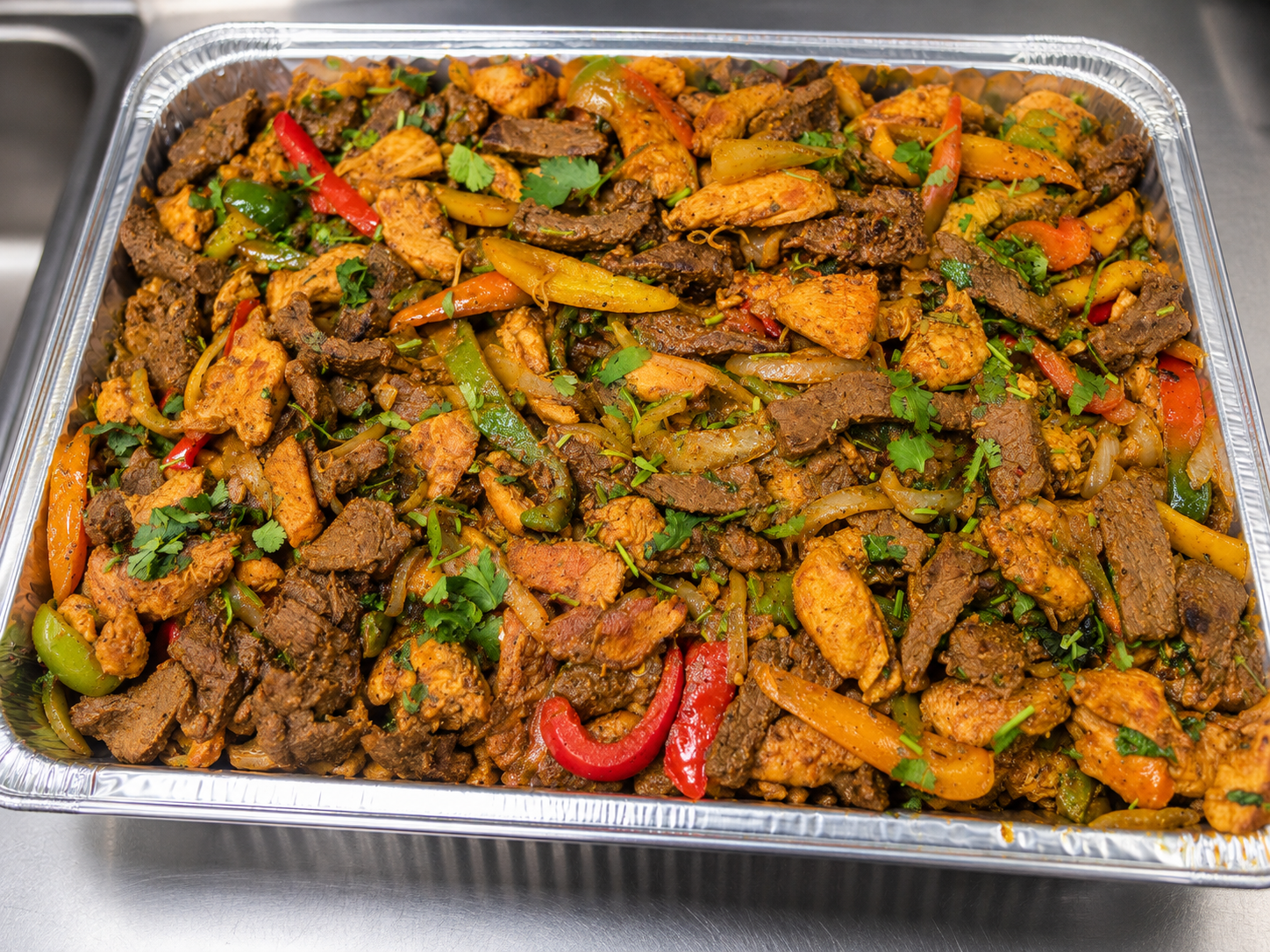 Catering tray with chicken, beef, peppers, and onions